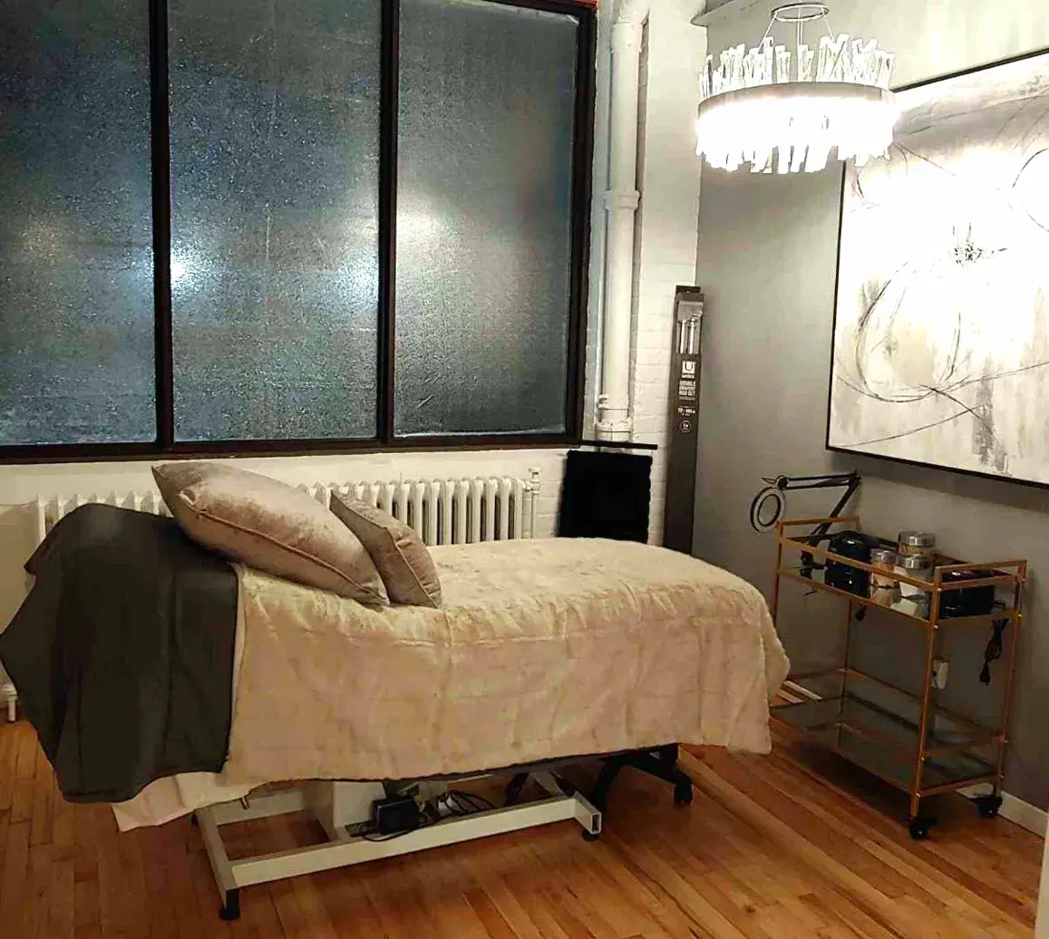 After: same treatment room finished in soft gray with treatment bed and chandelier