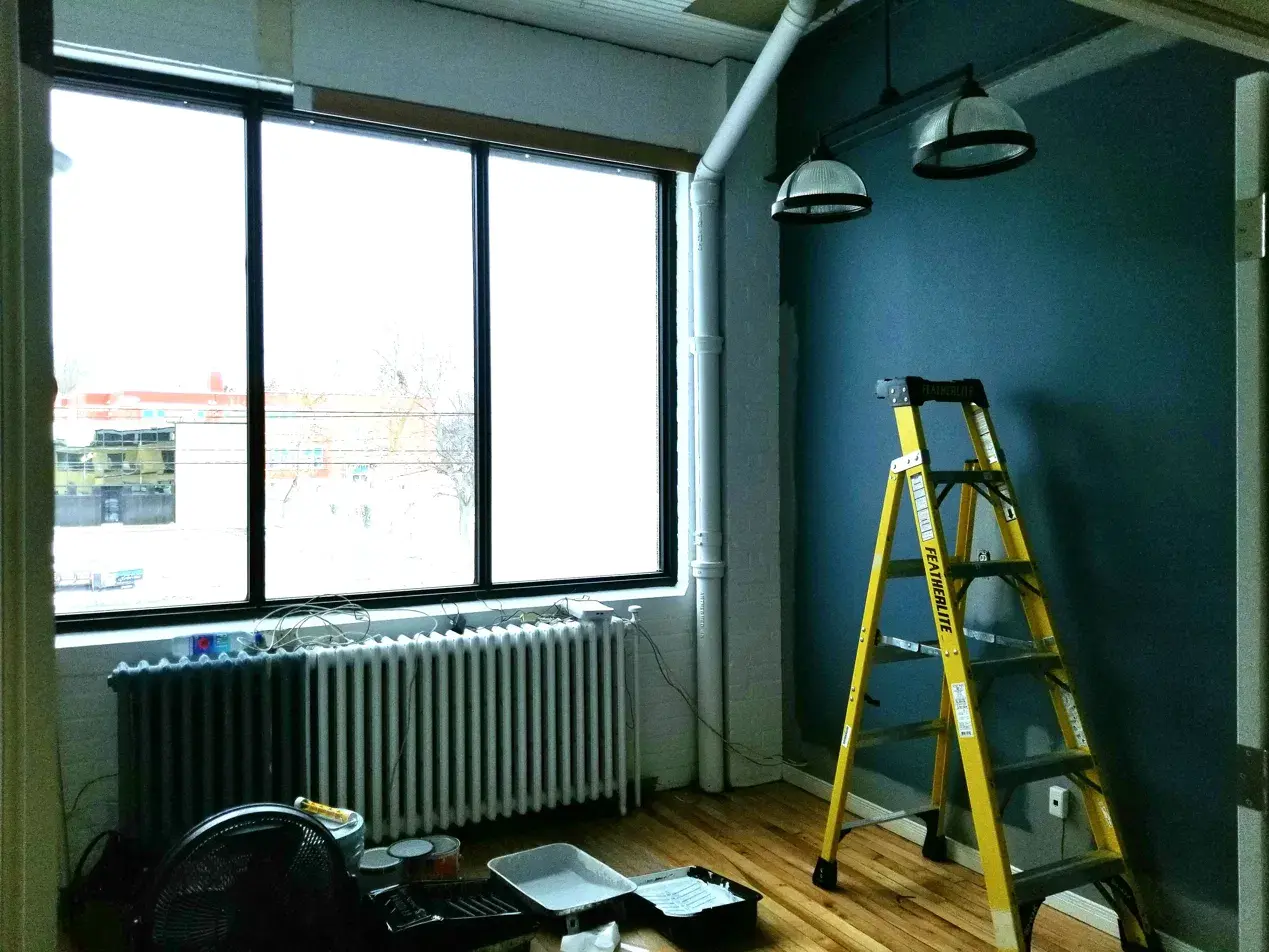 Before: treatment room with dark teal accent wall, exposed pipe and radiator