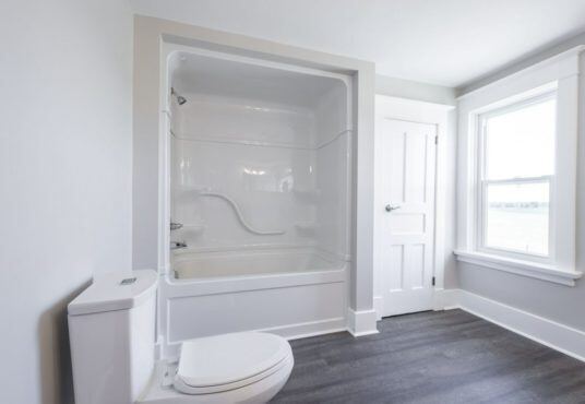 After: same room finished as a bathroom with tub, tile-look flooring and fresh paint