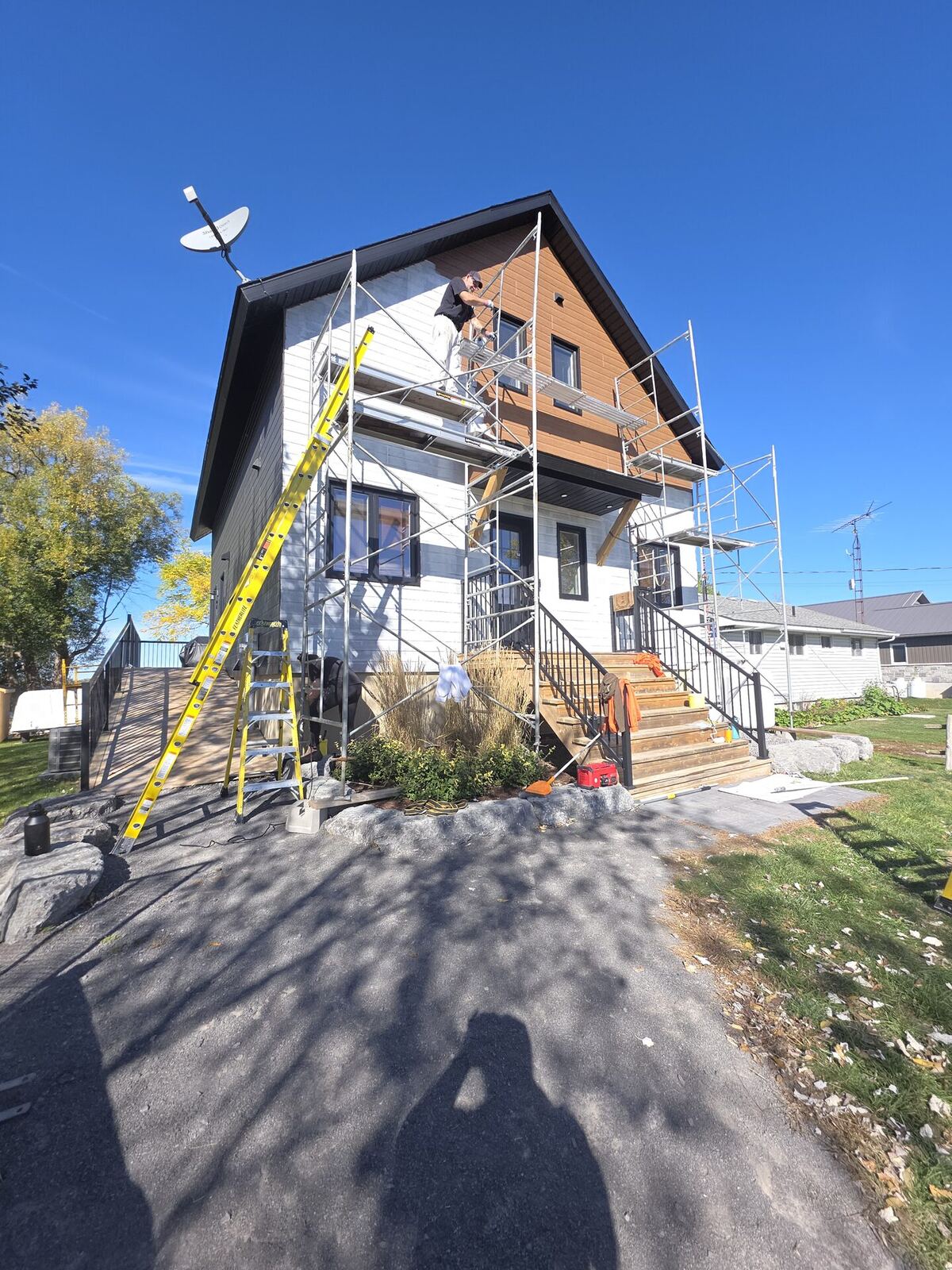 Before: two-tone brown and white lakeside exterior mid-project, scaffolding in place