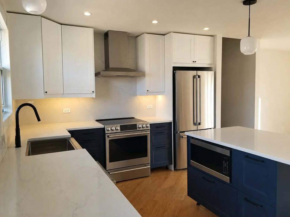 After: finished kitchen with navy cabinetry, quartz counters and stainless appliances